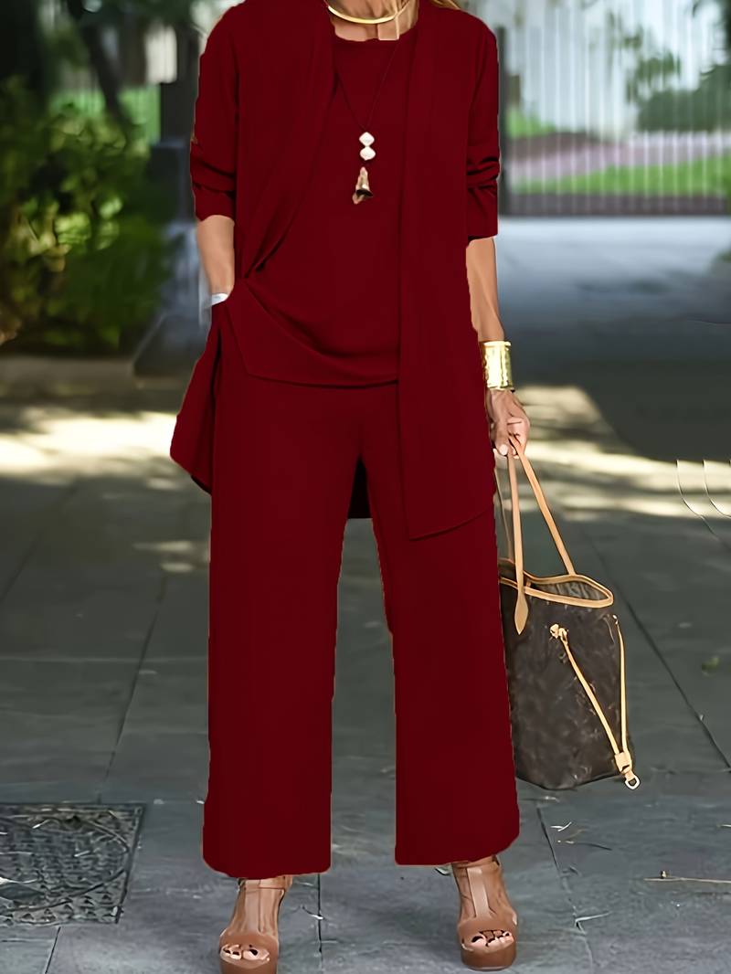 Donna in completo rosso elegante, con pantaloni larghi e giacca, indossa sandali con zeppa e borsa a mano marrone. Moda femminile urbana.