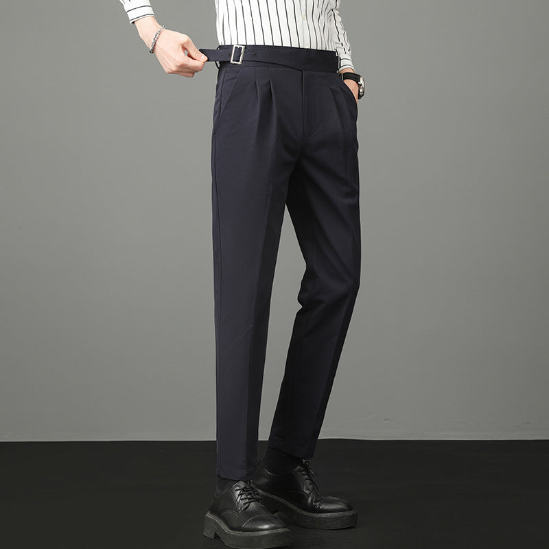 Pantaloni eleganti da uomo blu scuro, indossati con camicia a righe bianche e nere, scarpe nere. Stile formale, moda maschile contemporanea.