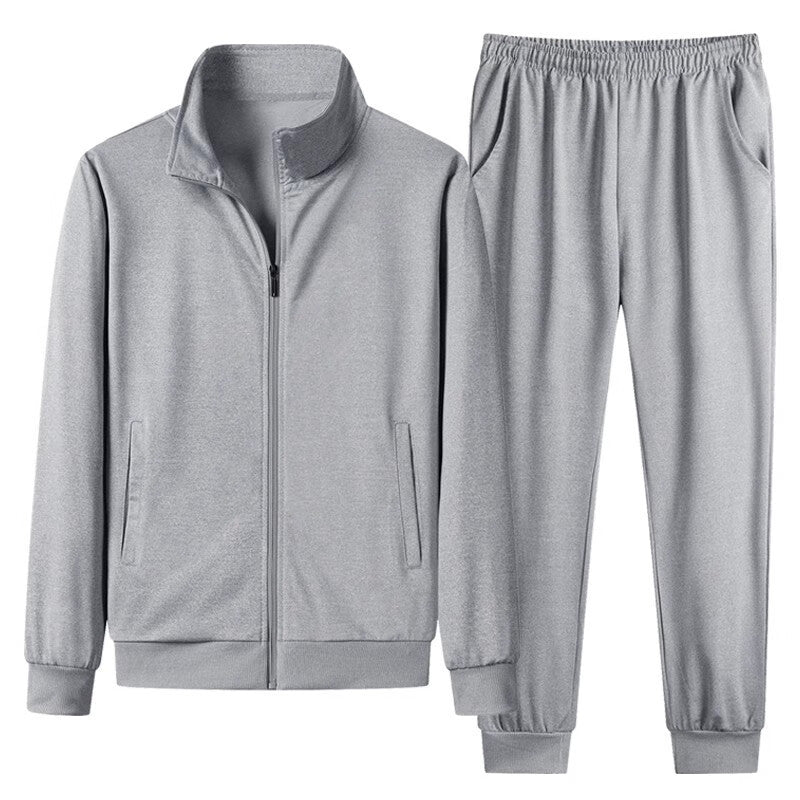 Tuta sportiva grigia in poliestere, composta da giacca con zip e pantaloni con elastico, ideale per allenamento e tempo libero.