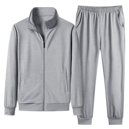 Tuta sportiva grigia in poliestere, composta da giacca con zip e pantaloni con elastico, ideale per allenamento e tempo libero.