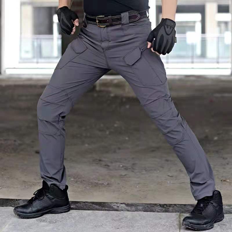 Pantaloni tattici grigi da uomo, resistenti e multifunzionali, con tasche cargo, indossati con guanti neri e scarpe robuste, ideali per outdoor.