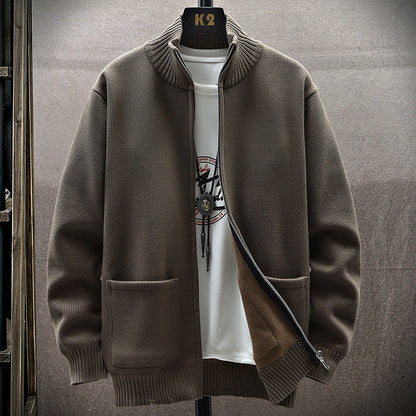 Giacca cardigan marrone con zip aperta, tasche frontali, su sfondo neutro. Indossata sopra una maglietta bianca con stampa grafica. Moda uomo casual.