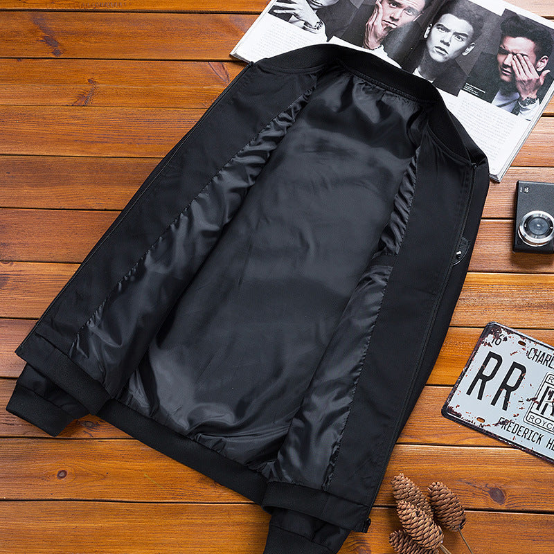 Giacca nera aperta su tavolo di legno, con rivista, fotocamera vintage e targa decorativa. Moda maschile, abbigliamento casual elegante.