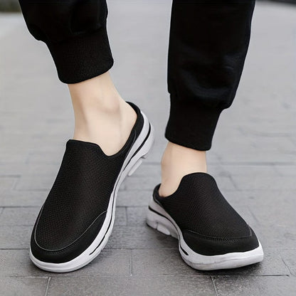 Scarpe slip-on nere da uomo su pavimento grigio, design casual e sportivo, suola bianca antiscivolo, ideali per passeggiate e tempo libero.