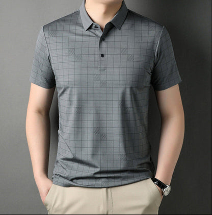 Uomo con polo grigia a quadri, maniche corte, sfondo grigio. Moda maschile elegante, abbigliamento casual, stile moderno.