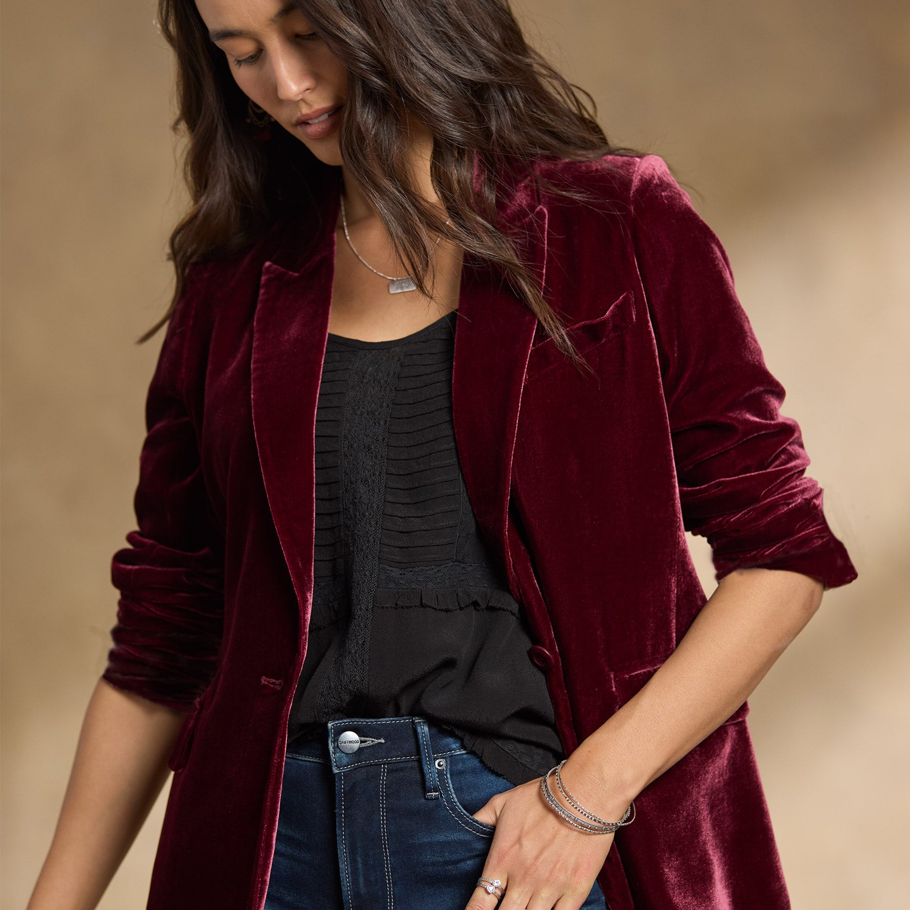 Donna con giacca di velluto bordeaux, top nero e jeans. Moda autunnale elegante, abbigliamento casual chic, tendenze moda 2023.