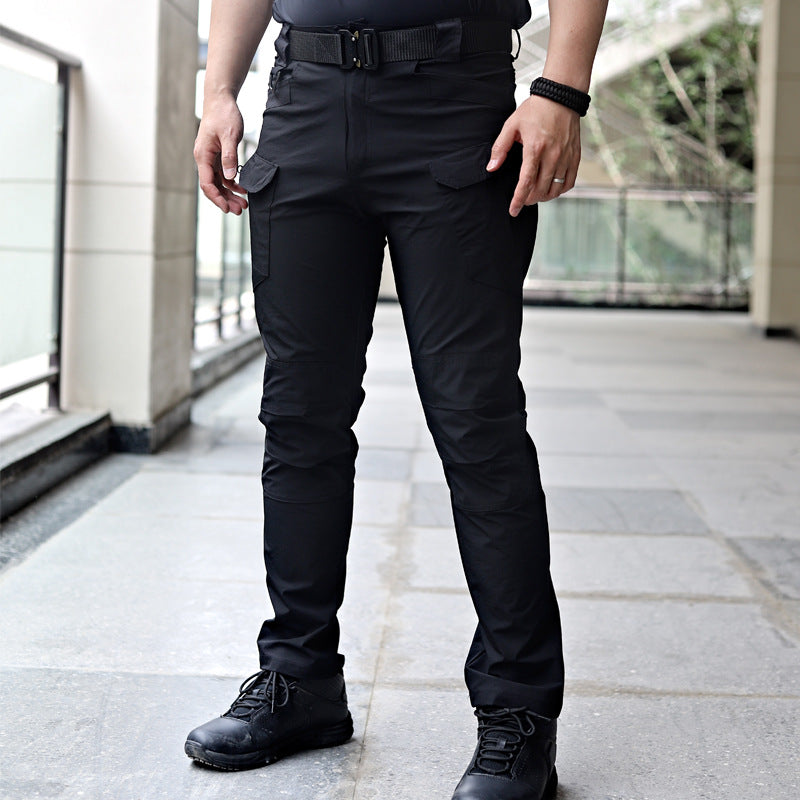 Pantaloni tattici neri da uomo, resistenti e multifunzionali, con tasche cargo, indossati con stivali neri su pavimento in pietra.