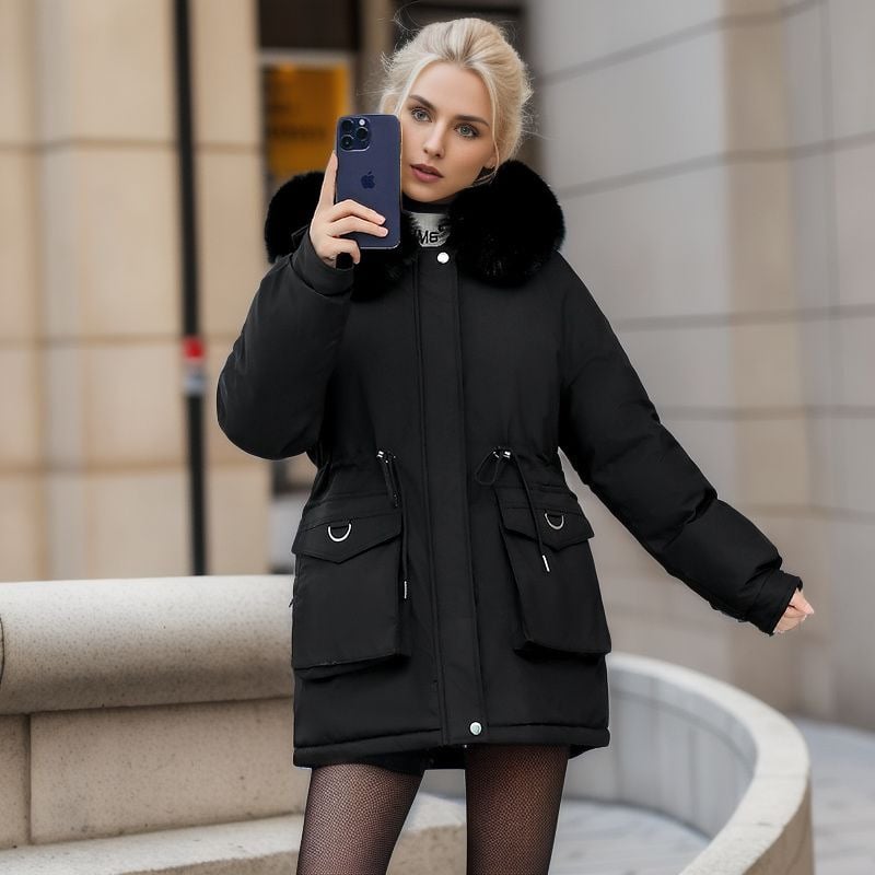 Donna con cappotto nero elegante, cappuccio in pelliccia, tiene uno smartphone blu. Moda invernale urbana, abbigliamento caldo e chic.