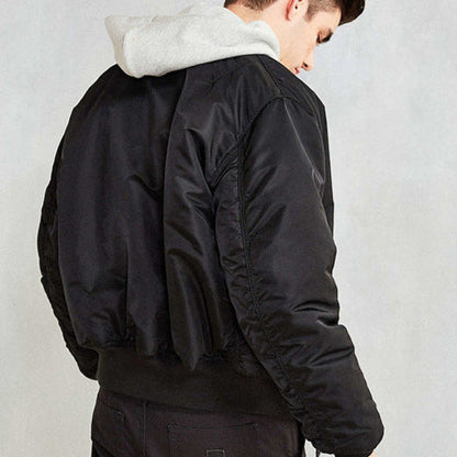 Giacca bomber nera uomo, tessuto lucido, indossata sopra felpa grigia con cappuccio. Moda casual, abbigliamento autunnale, stile urbano.