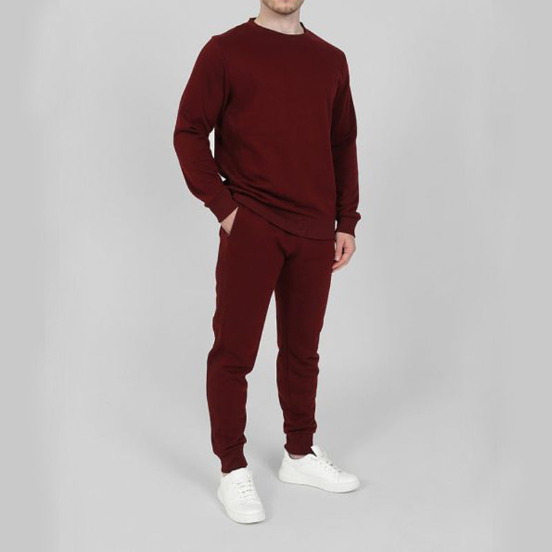 Uomo in tuta sportiva bordeaux, composta da felpa e pantaloni, con scarpe bianche. Abbigliamento casual e comodo per il tempo libero.