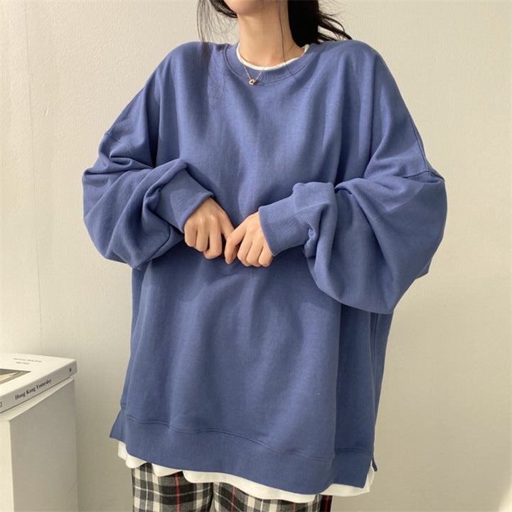 Donna con felpa oversize blu, maniche lunghe, indossa pantaloni a quadri. Stile casual, moda autunnale, abbigliamento comodo e trendy.