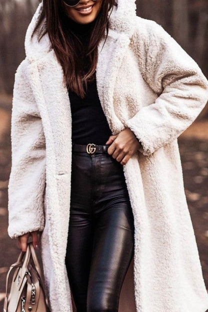 Donna con cappotto in pelliccia sintetica bianca, pantaloni in pelle nera, borsa beige e occhiali da sole. Moda autunnale, stile elegante.