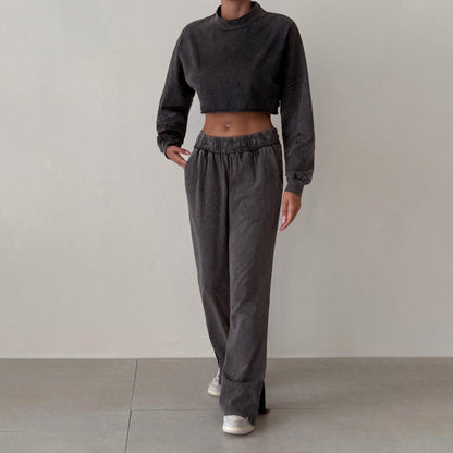 Donna in abbigliamento casual: felpa corta e pantaloni larghi grigi, scarpe da ginnastica bianche. Moda streetwear, stile comodo e moderno.