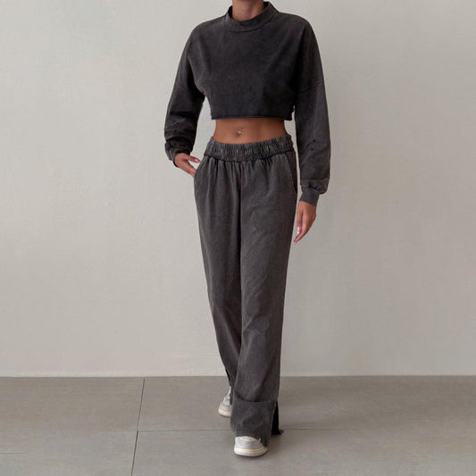 Donna in abbigliamento casual: felpa corta e pantaloni larghi grigi, scarpe da ginnastica bianche. Moda streetwear, stile comodo e moderno.