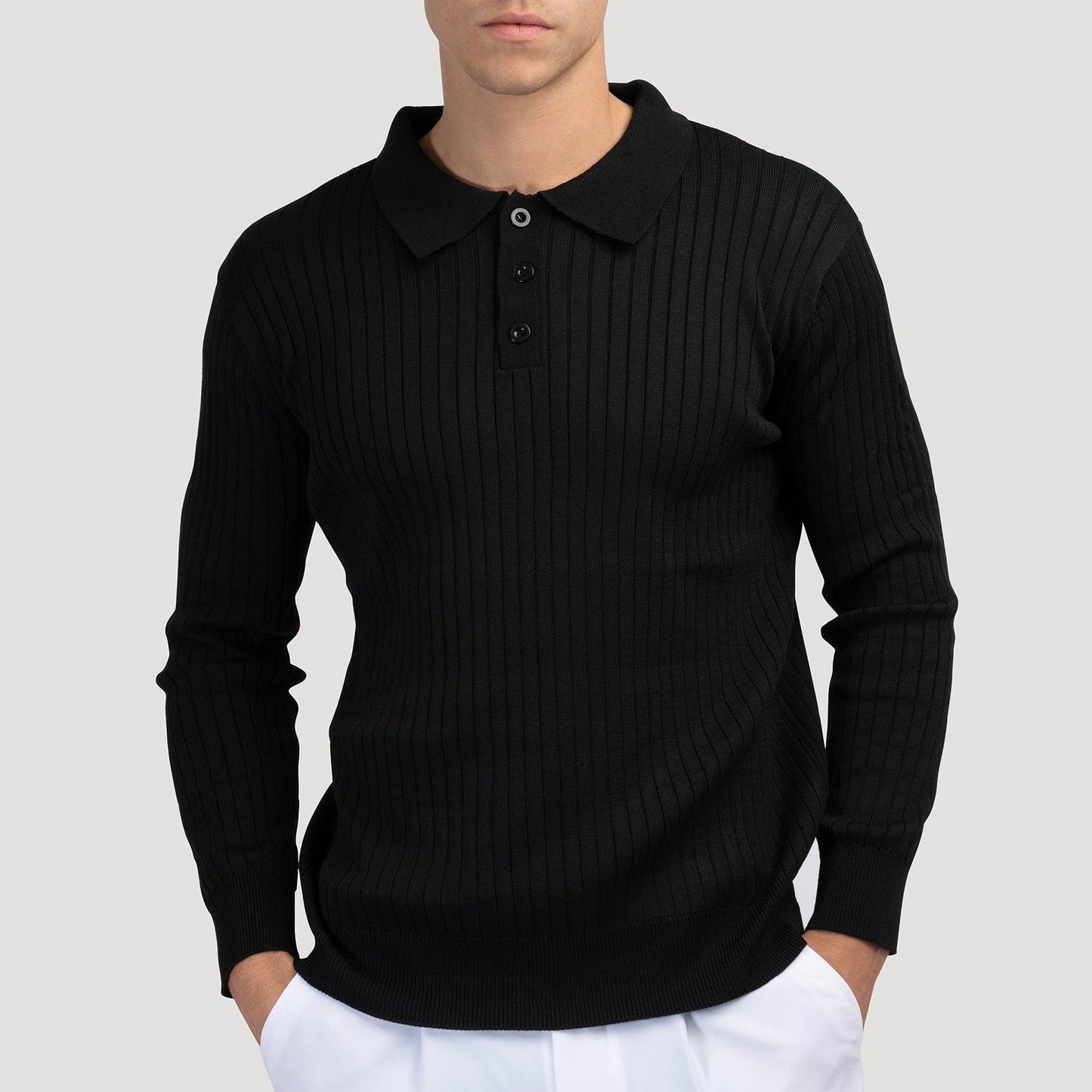 Maglione uomo nero a coste con colletto e bottoni, indossato su pantaloni bianchi. Moda maschile elegante, abbigliamento casual chic.