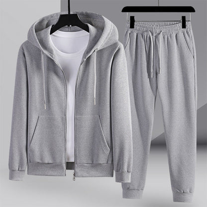 Tuta sportiva grigia da uomo con felpa con cappuccio e pantaloni, tessuto a coste, ideale per abbigliamento casual e sportivo.