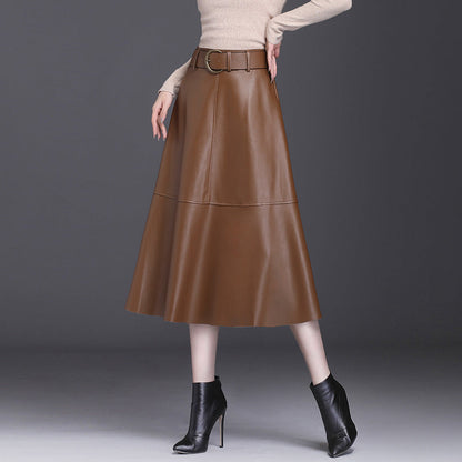 Gonna midi in pelle marrone con cintura, abbinata a stivaletti neri e maglione beige. Moda autunnale elegante e chic per donna.