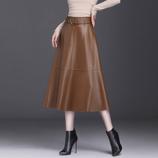 Gonna midi in pelle marrone con cintura, abbinata a stivaletti neri e maglione beige. Moda autunnale elegante e chic per donna.