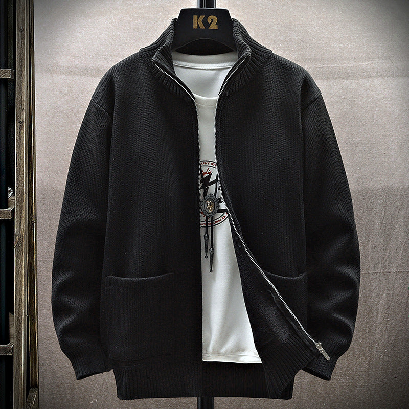 Giacca nera in maglia con zip, colletto rialzato, su gruccia K2, sopra maglietta bianca con stampa. Moda uomo, abbigliamento casual elegante.