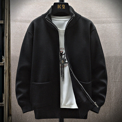 Giacca nera in maglia con zip, colletto rialzato, su gruccia K2, sopra maglietta bianca con stampa. Moda uomo, abbigliamento casual elegante.