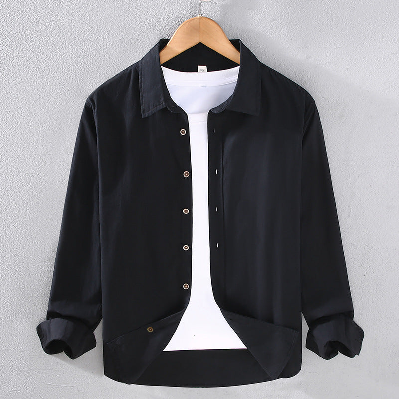 Camicia nera casual da uomo su gruccia, con bottoni e maniche lunghe, indossata sopra una maglietta bianca. Moda maschile elegante e moderna.