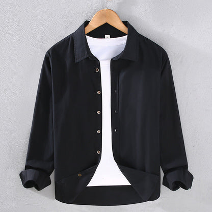 Camicia nera casual da uomo su gruccia, con bottoni e maniche lunghe, indossata sopra una maglietta bianca. Moda maschile elegante e moderna.