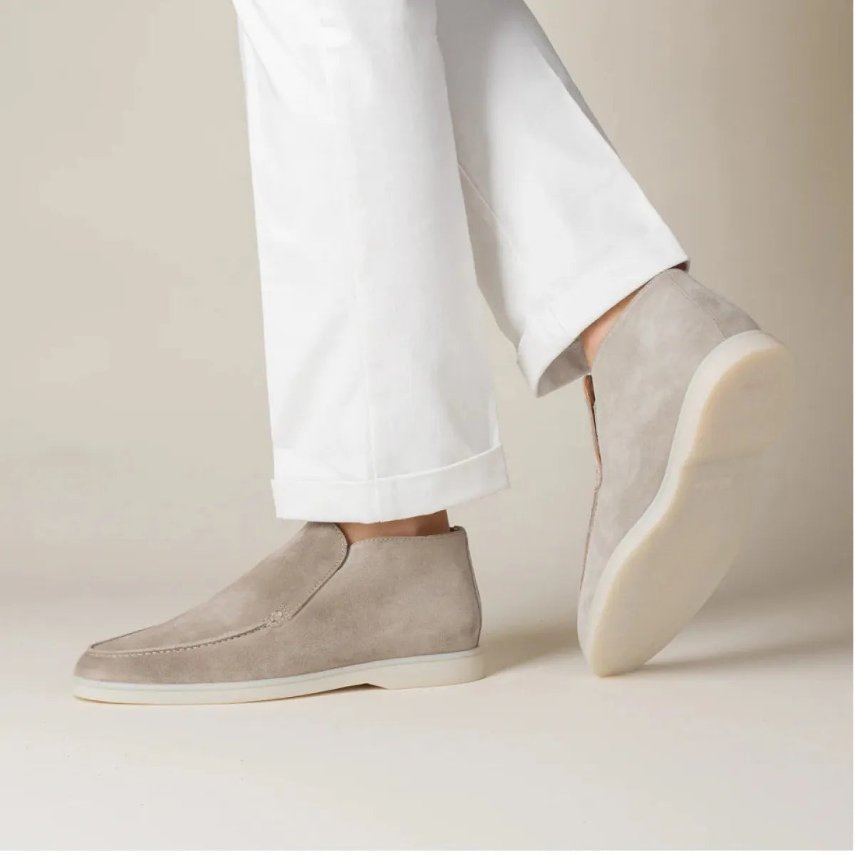 Scarpe uomo in pelle scamosciata beige, design elegante, abbinate a pantaloni bianchi. Calzature moda, stile casual-chic, suola chiara.
