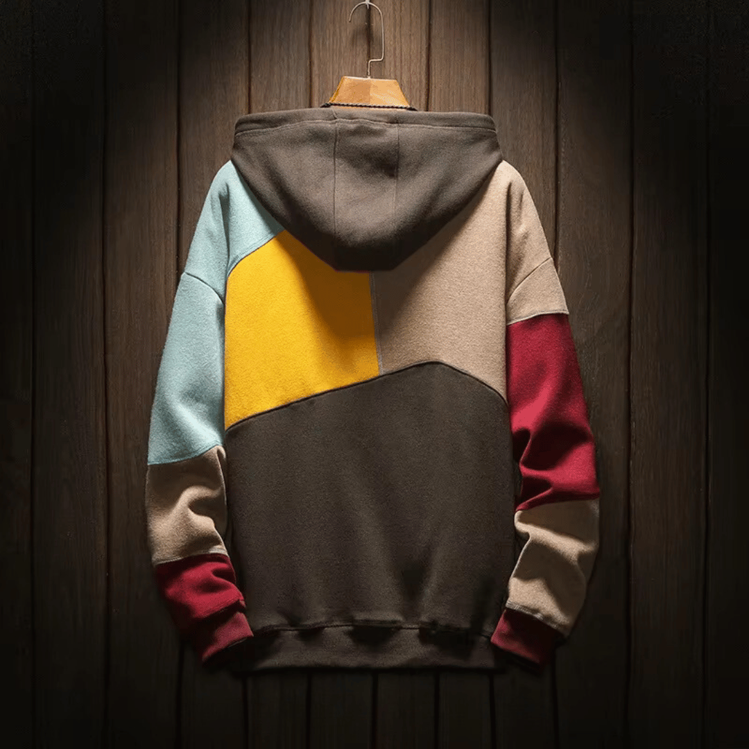 Felpa con cappuccio multicolore, design a blocchi, appesa su sfondo in legno. Moda casual, abbigliamento autunnale, stile urbano.