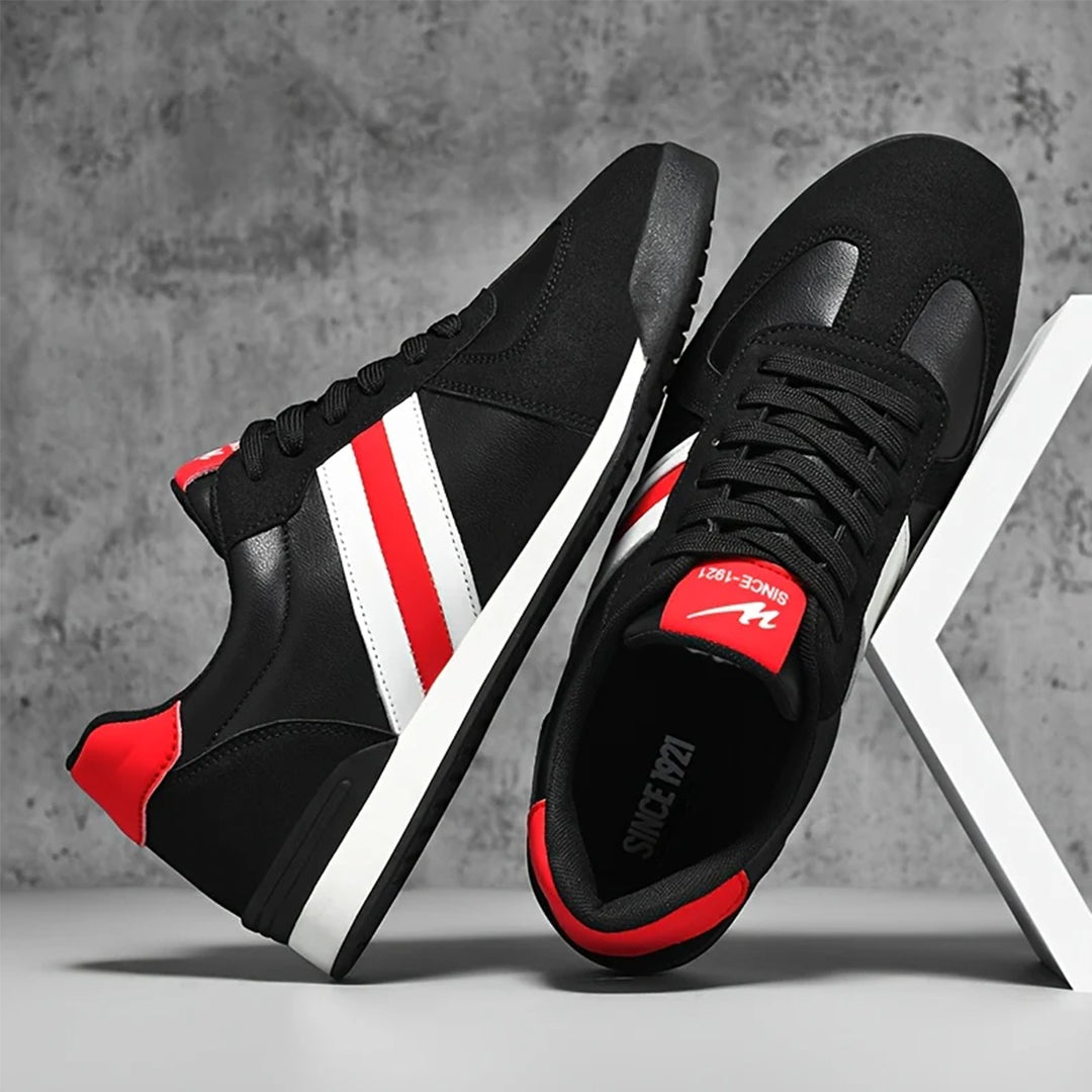 Scarpe da ginnastica nere con strisce bianche e rosse, suola in gomma, design moderno, sfondo grigio. Sneakers uomo moda 2023.