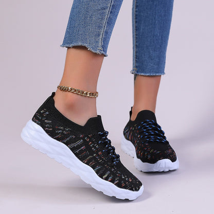 Scarpe da ginnastica nere con suola bianca, indossate con jeans. Design moderno, lacci blu, perfette per moda casual e sportiva.