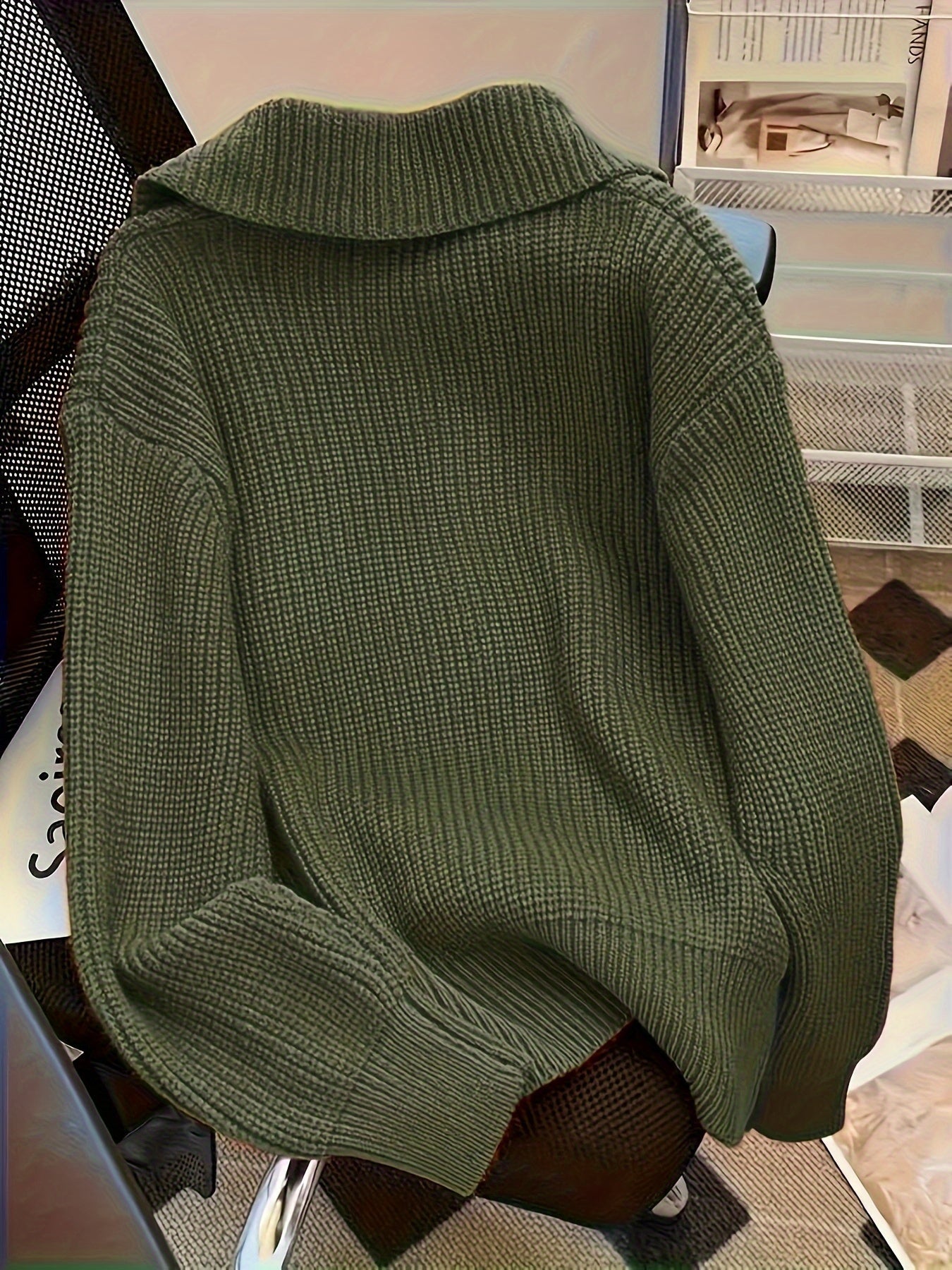 Maglione verde oliva a maglia grossa su sedia, design casual e accogliente, perfetto per moda autunnale e invernale, stile caldo e confortevole.