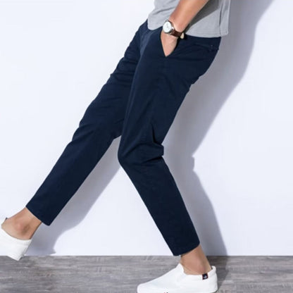 Pantaloni chino blu scuro uomo, abbinati a scarpe bianche casual e maglietta grigia, moda maschile elegante e moderna.