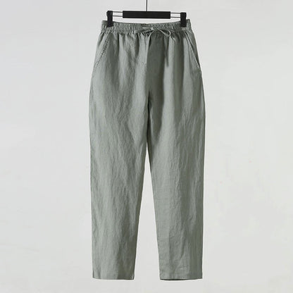 Pantaloni casual grigi da uomo in cotone, con elastico in vita e tasche laterali, appesi su gruccia. Abbigliamento comodo e versatile.