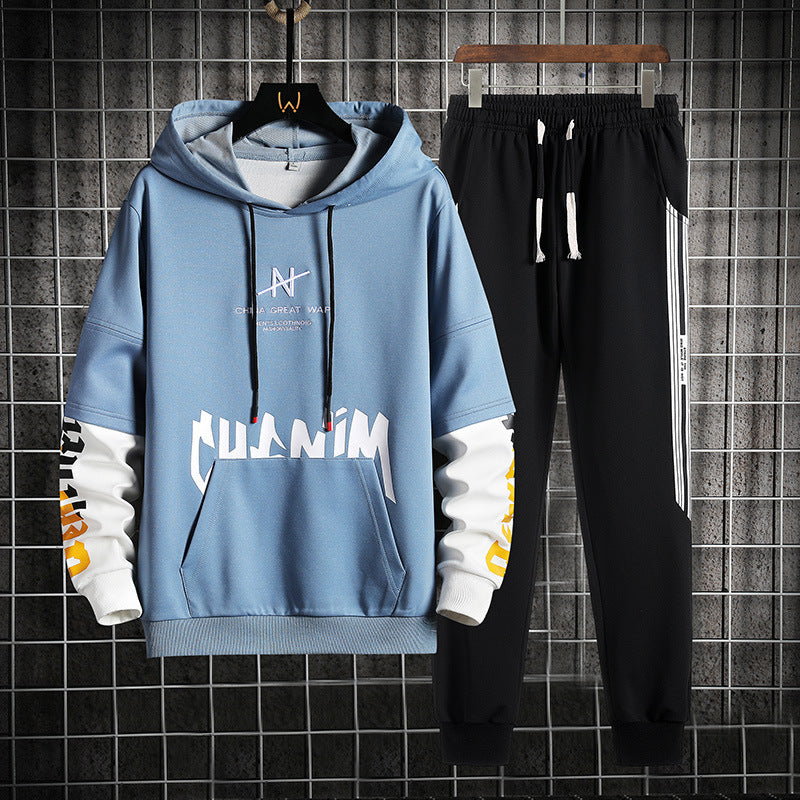 Tuta sportiva uomo: felpa con cappuccio blu e pantaloni neri, design moderno, scritte bianche e gialle, ideale per abbigliamento casual e sportivo.