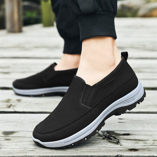 Scarpe da passeggio nere su una passerella di legno, design slip-on, suola antiscivolo, ideali per attività all'aperto e comfort quotidiano.