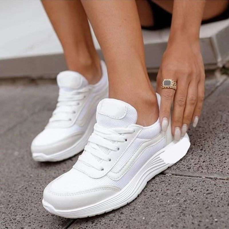 Scarpe da ginnastica bianche da donna, design moderno con suola spessa, indossate su pavimento grigio. Scarpe sportive eleganti e comode.