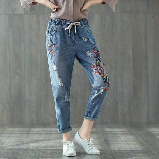 Jeans donna ricamati con fiori, strappati, stile casual, abbinati a scarpe bianche. Moda femminile, abbigliamento trendy, pantaloni denim.