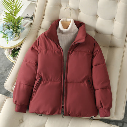 Giacca invernale imbottita rossa su divano beige, con collo alto e zip, perfetta per moda autunno inverno. Stile casual e caldo.
