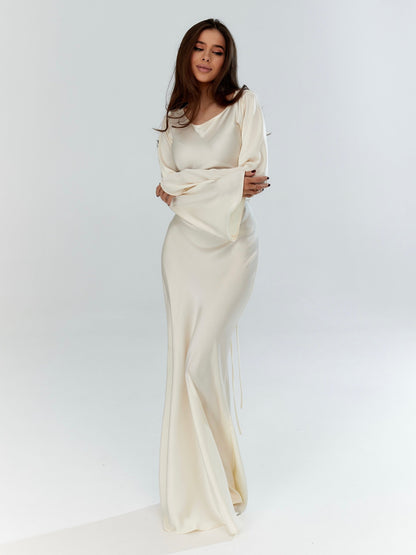 Donna in abito da sera bianco elegante, maniche lunghe, posa su sfondo bianco. Moda femminile, abbigliamento elegante, stile sofisticato.