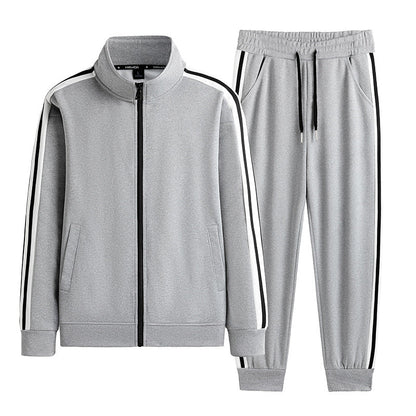 Tuta sportiva grigia da uomo con giacca a zip e pantaloni, dettagli a righe nere e bianche, ideale per allenamento e tempo libero.