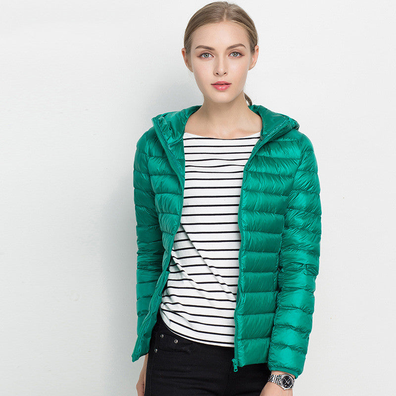 Donna con giacca piumino verde, cappuccio, indossa maglia a righe bianche e nere. Moda autunnale, abbigliamento casual elegante.