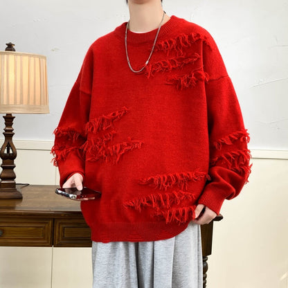 Maglione rosso oversize con dettagli sfrangiati, indossato da una persona. Moda casual autunnale, stile streetwear. Lampada e tavolo in legno sullo sfondo.