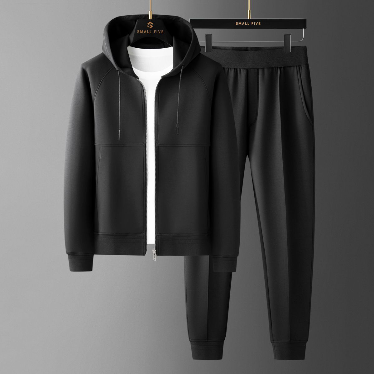 Tuta sportiva nera con felpa con cappuccio e pantaloni, appesa su grucce. Abbigliamento casual uomo, moda streetwear, stile moderno.