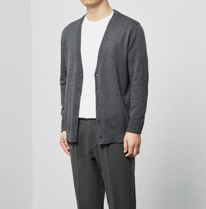 Uomo con cardigan grigio scuro su maglietta bianca, pantaloni eleganti grigi. Moda maschile casual, abbigliamento autunnale, stile minimalista.