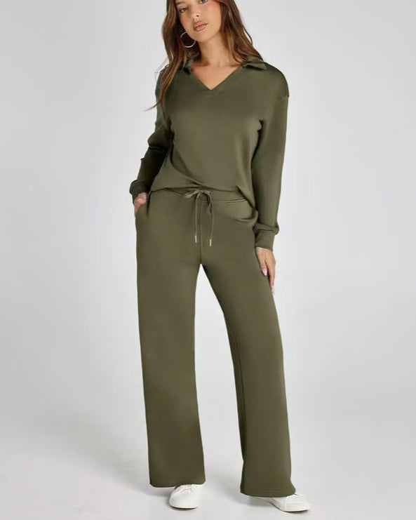 Donna in tuta verde oliva, felpa con cappuccio e pantaloni larghi, posa casual su sfondo bianco. Abbigliamento comodo e alla moda.