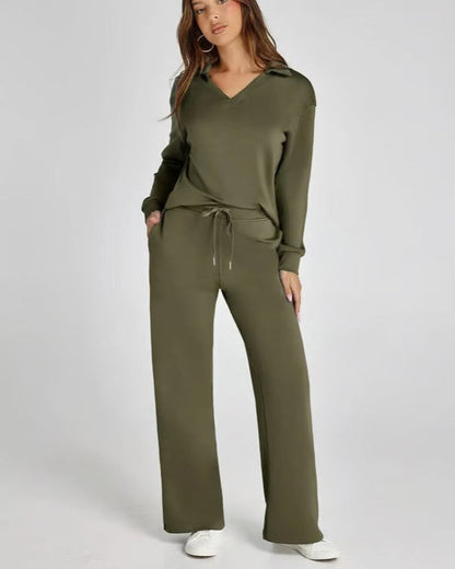 Donna in tuta verde oliva, felpa con cappuccio e pantaloni larghi, posa casual su sfondo bianco. Abbigliamento comodo e alla moda.
