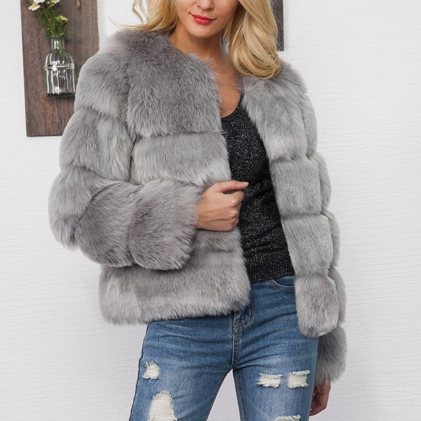 Donna con giacca di pelliccia grigia, maglia nera scintillante e jeans strappati. Moda invernale elegante, abbigliamento casual chic.