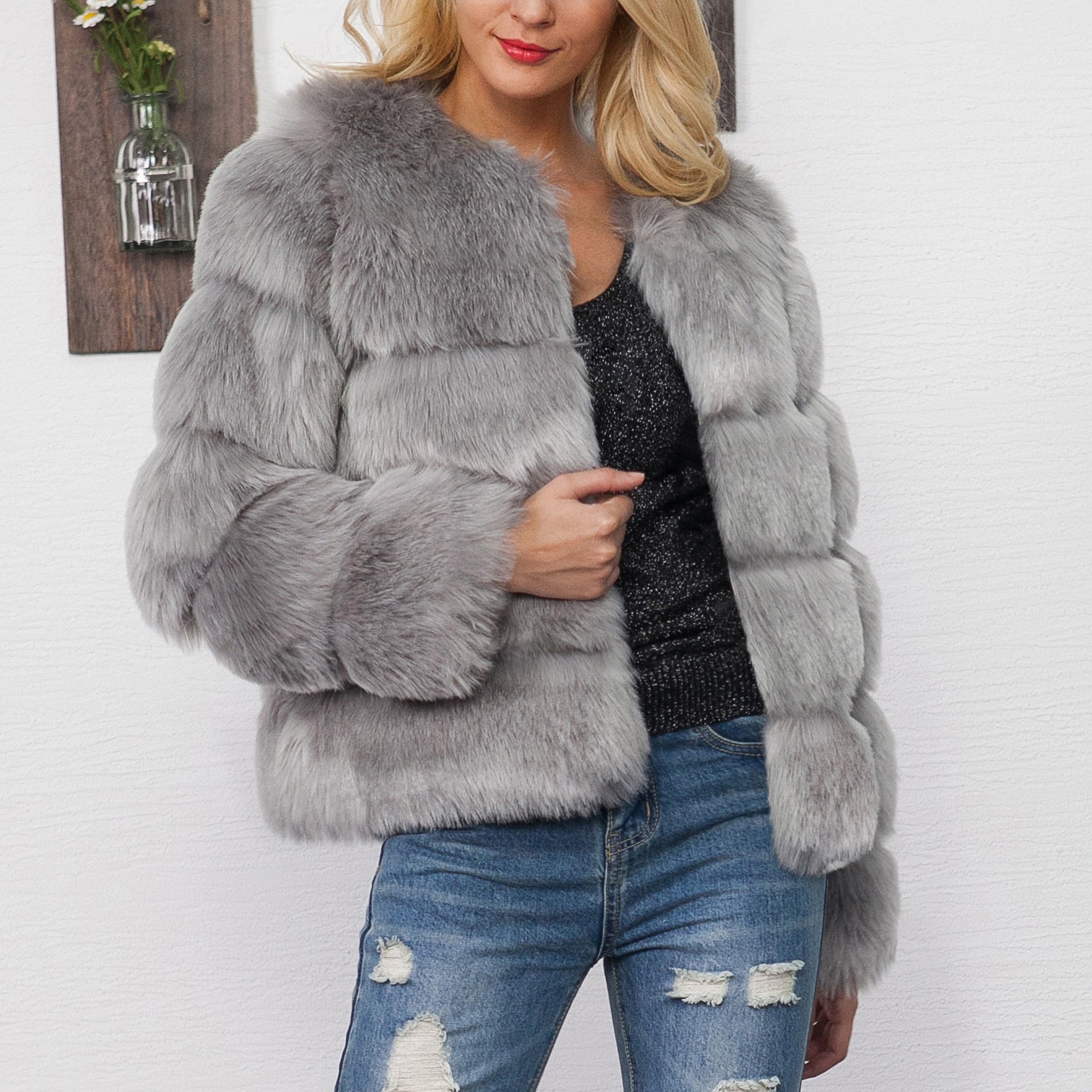 Donna con giacca di pelliccia grigia, maglia nera scintillante e jeans strappati. Moda invernale elegante, abbigliamento casual chic.