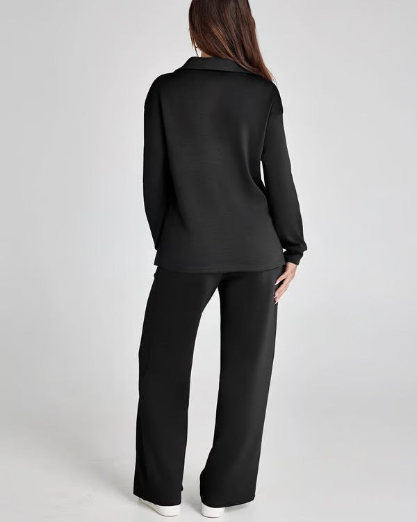 Donna in abbigliamento casual nero, vista posteriore. Indossa maglia e pantaloni larghi, scarpe bianche. Stile minimalista, moda donna.