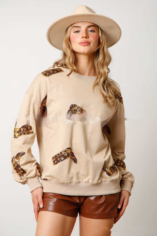 Donna con cappello beige, maglione con paillettes marroni e pantaloncini in pelle marrone. Moda autunnale, abbigliamento casual chic.